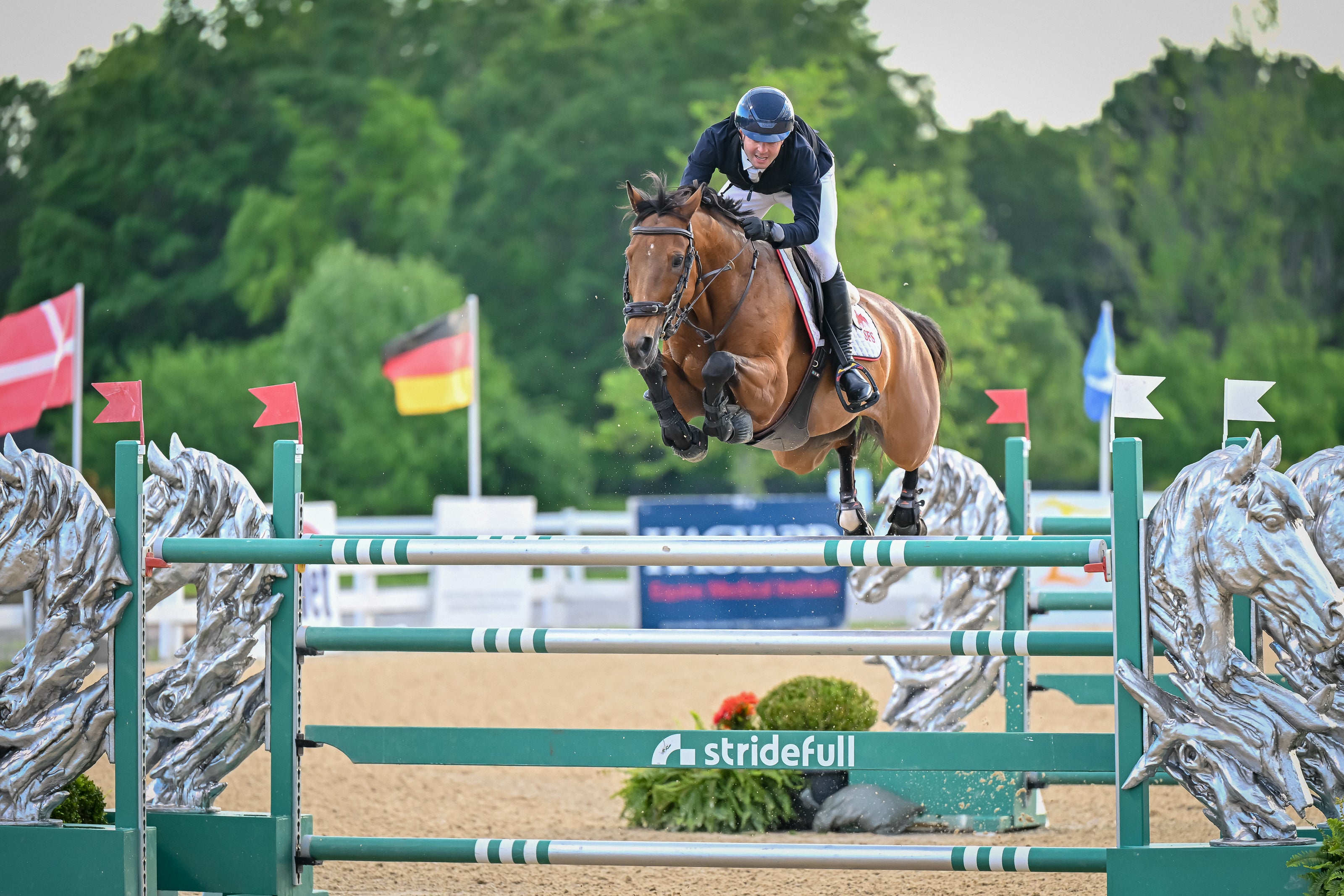 Horse and rider jumping over an obstacle at a equestrian event with 'stridefull' branding.